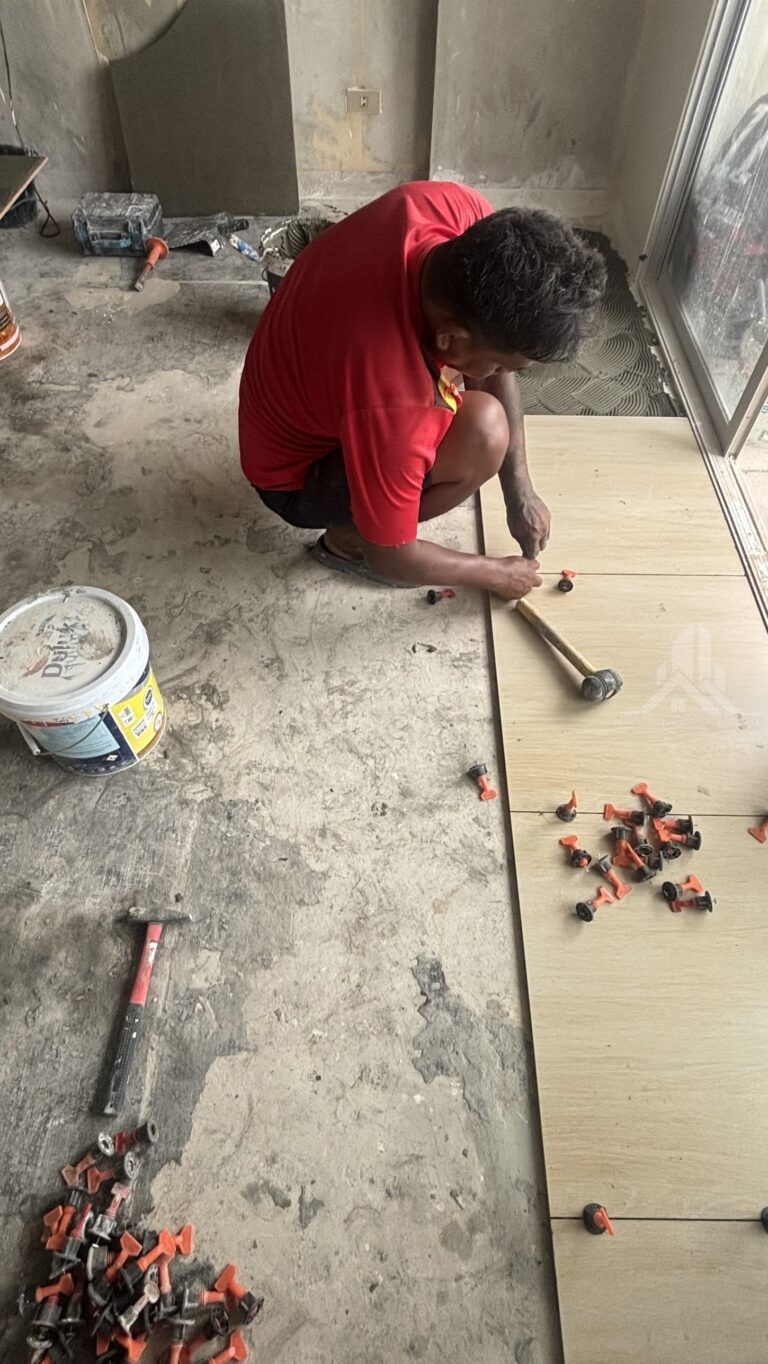 Worker laying wood-look floor tiles with levelling clips during a studio renovation at Jomtien Condotel Chain, Jomtien Soi 16, Pattaya