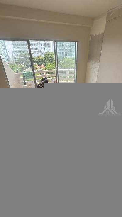 Large-format wood-look porcelain floor tiles being laid with leveling clips in a jomtien condo living room during renovation